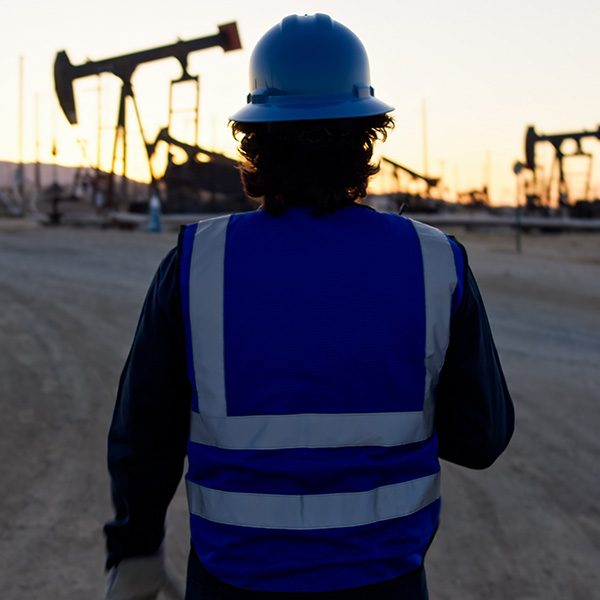 Oilfield Worker Looking at Pump Jacks at Sunset